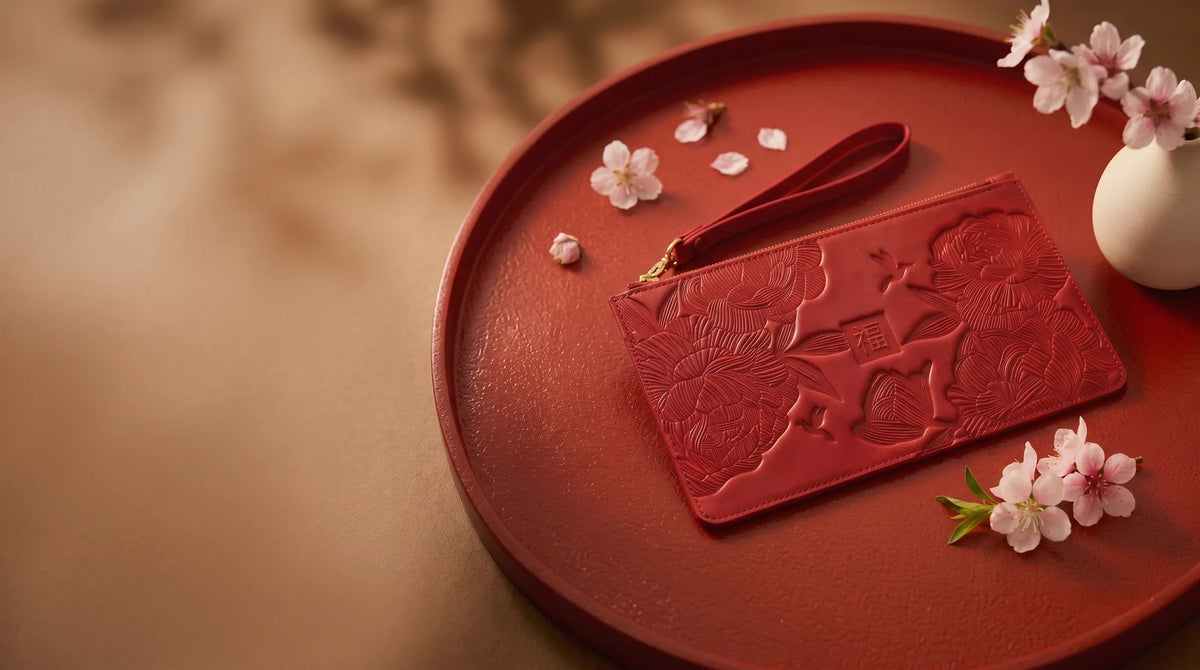 Debossed red leather travel pouch with cherry blossom on a lacquer tray.